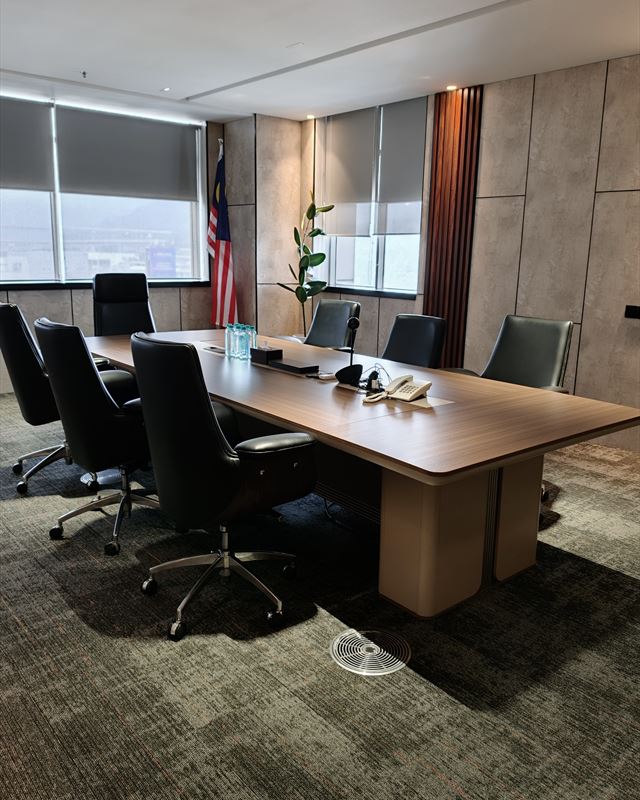 Boardroom with a timber table, leather chairs and the Malaysian flag