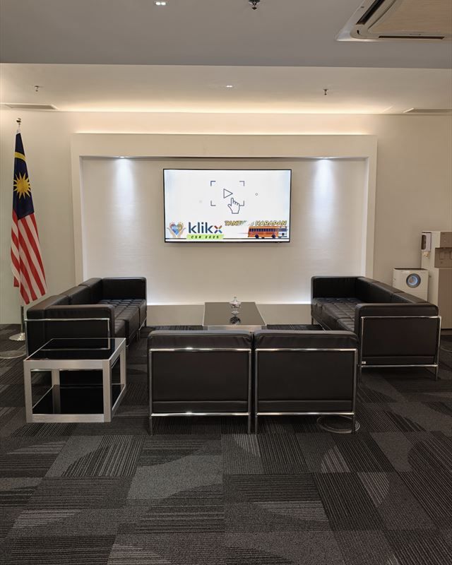 Reception lounge with leather sofas facing a screen showing the Klikx CSR 2025 slide