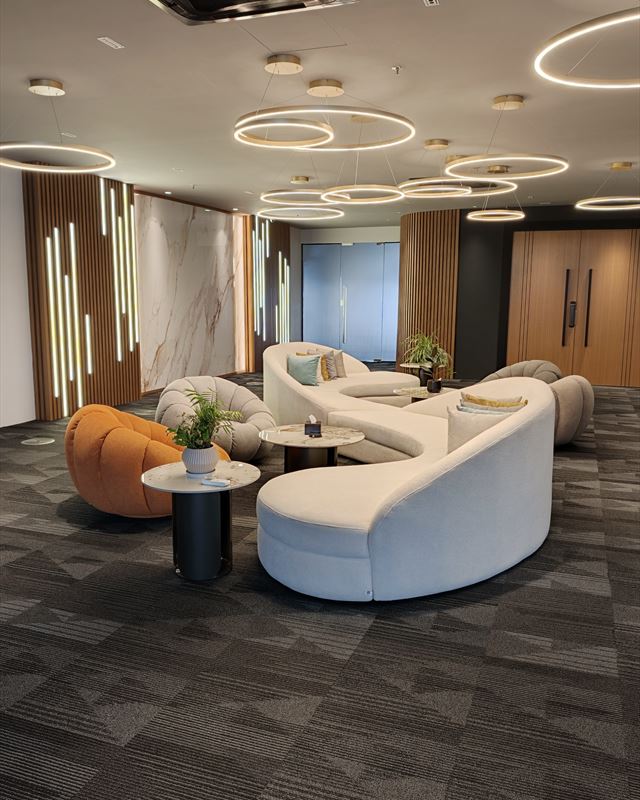 Lounge with curved white sofas under ring lights