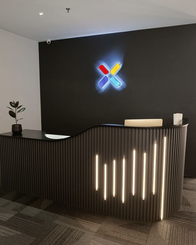 Reception, with the lit Klikx x on the wall behind the desk